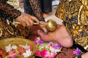traditionelle javanische Braut, der Vorgang des Reinigens der Füße des Mannes mit Blumen für javanische Bräute foto