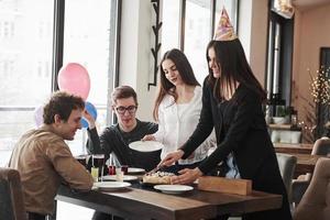 schneiden Sie diesen köstlichen Kuchen. einer der mitarbeiter hat heute geburtstag. Freundliche Mitarbeiter beschlossen, eine Überraschung für sie zu machen foto