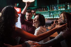 Alle wollen dieses Mädchen umarmen. Schöne Jugendliche feiern zusammen mit Alkohol im Nachtclub foto