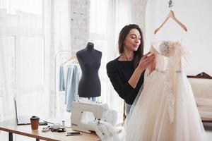 Blick auf ein Kleid. Modedesignerin arbeitet in der Werkstatt an den neuen Kleidern foto