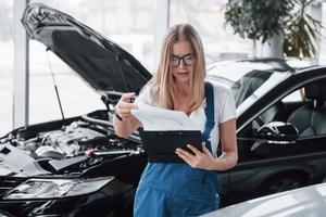 Grafiken und andere Informationen. manager mit notizblock, im weißen hemd und in blauer uniform steht mit aufgesetzter verdeck vor auto foto