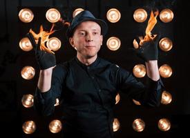 professioneller illusionist in schwarzem hut, hemd und glühen, die mit feuer spielen foto