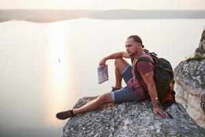 Attraktiver Mann, der den Blick auf die Berglandschaft über der Wasseroberfläche genießt. Reise-Lifestyle-Abenteuer-Urlaub-Konzept foto