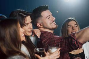 kann die Kamera nicht sehen, aber Sie können das an der Handposition erkennen. freunde, die selfie im schönen nachtclub machen foto