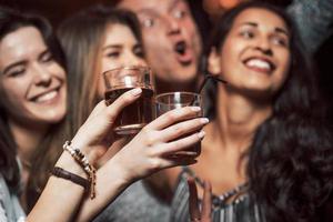 aktive Jugend. Fröhliche Menschen tanzen im Luxus-Nachtclub zusammen mit verschiedenen Getränken in der Hand foto