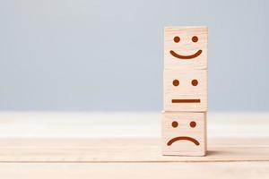Lächelngesichtssymbol auf gelben Holzwürfelblöcken. Emotion, Servicebewertung, Ranking, Kundenbewertung, Zufriedenheit und Feedback-Konzept foto