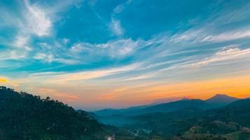 schöne naturlandschaft der bergkette mit sonnenunterganghimmel und wolken. ländliches Dorf im Bergtal in Thailand. Landschaft der Bergschicht in der Abenddämmerung. Tropenwald. natürlichen Hintergrund.