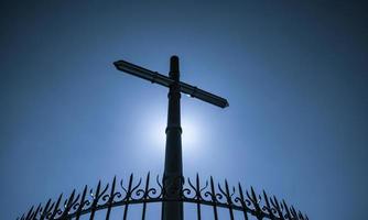 edelstahlkreuz und zaun auf blauem himmel und sonnenlichthintergrund. Kruzifix von Jesus Christus. gottlicht und vergebungskonzept. Kreuze, christliche Symbole. Glaube an Gott. Symbol des Glaubens. Ostern. foto