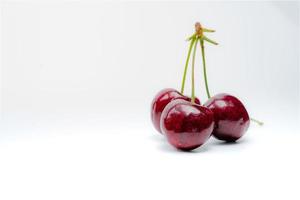 rote Kirsche mit Stiel isoliert auf weißem Hintergrund. reife rote Süßkirsche. süße und saftige Bio-Kirsche. frisches obst für sommerdessert. antioxidative Nahrung. gesunder Snack. foto