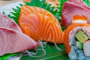 japanisches lebensmittelset serviert auf weißem teller. Lachs-Sushi und Sashimi am Tisch im Restaurant. frisches rohes Fischfleisch in Scheiben geschnitten und Reisrollen mit japanischem Essig mit Meeresfrüchten und Gemüse. Gesundes japanisches Essen. foto