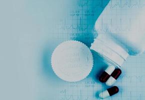 kapselpillen und geöffnete flasche und ekg- oder ekg-elektrokardiogramm-diagrammpapier. est Ergebnis des Belastungstests. medizin mit herzproblemkonzept foto