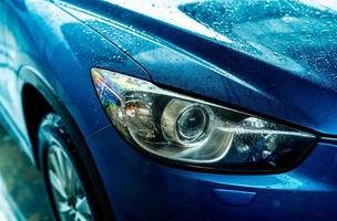 blaues auto wäscht sich mit wasser. Autopflegegeschäft. Auto mit Wassertropfen nach der Reinigung mit Hochdruckwasserspray. Autoreinigung vor dem Wachsservice. Fahrzeugreinigungsservice mit Antiseptikum. foto