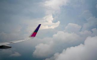 Flügel des Flugzeugs über der Stadt. Flugzeug fliegt am blauen Himmel. malerische Aussicht aus dem Flugzeugfenster. Flug der kommerziellen Fluggesellschaft morgens mit Sonnenlicht. Flugzeugflügel über Wolken. Konzept der Flugmechanik. foto