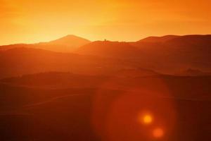 Toskana-Landschaft bei Sonnenaufgang, Italien. toskanische Hügel, Sonneneruption foto