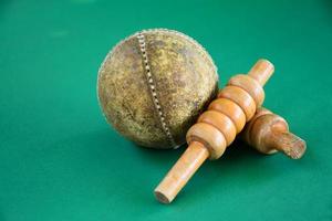 Nahaufnahme alter Cricket-Sportgeräte auf grünem Boden, alter Lederball und hölzerne Pforten, weicher und selektiver Fokus, traditionelle Cricket-Sportliebhaber auf der ganzen Welt Konzept. foto