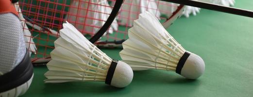 Badminton-Sportgeräte auf Federbällen auf grünem Boden, Schläger, Schuhe, selektiver Fokus auf Federbälle, Badminton-Sport-Liebhaber-Konzept. foto
