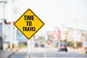 Verkehrsschild mit gelbem Etikett auf weißer Stange mit Texten "Zeit zum Reisen", Konzept zur Information der Fahrer, die Arbeit einzustellen und Zeit mit Reisen zu verbringen, um das Leben glücklich zu machen. foto