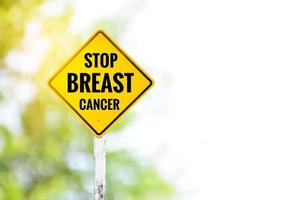 gelbes Etikett Verkehrsschild Stop Brustkrebs auf Zementpfosten neben der Landstraße mit verschwommenem Hintergrund, Kampagne für Fahrer zur Unterstützung von Frauenorganisationen, die für Brustkrebspatientinnen arbeiten. foto