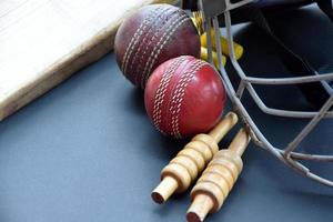 alte trainings-cricket-sportgeräte auf dunklem boden, lederball, wickets, helm und holzschläger, weicher und selektiver fokus, traditionelle cricket-sportliebhaber auf der ganzen welt. foto