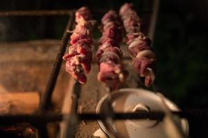 Fleisch mit Rauch auf dem Grill. Gebratenes Schweine-, Rind- und Lammfleisch am Spieß wird am Feuer gebraten, Spieße am Metallspieß werden im Freien gegrillt. Picknick-Konzept foto