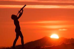 Saxophonist spielt bei Sonnenuntergang foto