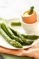 grüner Spargel mit weich gekochtem Ei auf weißem Teller