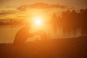 Silhouetten von Mutter und kleiner Tochter, die bei Sonnenuntergang spazieren gehen foto