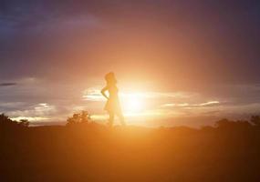 Silhouette einer Frau, die über einem schönen Himmelshintergrund betet foto