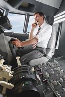 Geschäftsmann, der Flugzeug im Cockpit fährt und Handy benutzt foto