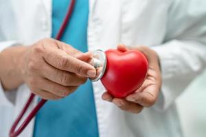 Arzt, der ein rotes Herz in der Krankenstation hält, gesundes, starkes medizinisches Konzept. foto