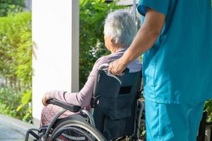 Pflegekraft hilft und pflegt asiatische Senioren oder ältere Frauen, die im Rollstuhl auf der Rampe im Pflegekrankenhaus sitzen, gesundes, starkes medizinisches Konzept foto