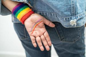 asiatische dame mit regenbogenflaggenarmbändern, symbol des lgbt-stolzmonats, feiert jährlich im juni die sozialarbeit von schwulen, lesbischen, bisexuellen, transgendern und menschenrechten. foto