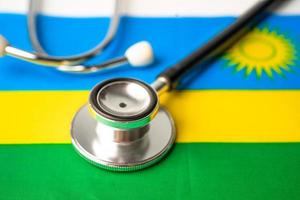 Schwarzes Stethoskop auf Ruanda-Flaggenhintergrund, Geschäfts- und Finanzkonzept. foto