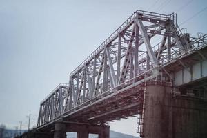 Eisenbahnbrücke aus Metallträgern und Betonsockel.