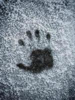 Handabdruck auf einer mit Reif bedeckten Oberfläche. gefrorener Handabdruck der rechten Hand im Schnee. foto