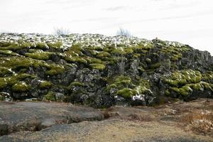 vulkanische Lavafelsen, die mit Moos und Schnee bedeckt sind foto