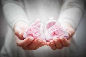 kleine babyschuhe in den händen. Konzepte des Wartens auf ein Kind, Wohltätigkeit, Mutter usw. foto