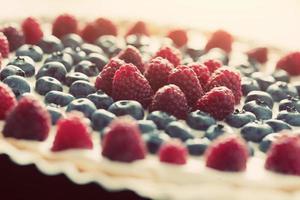 Obsttorte mit frischen Himbeeren und Heidelbeeren. Vintage-Licht foto