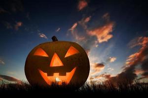 halloween-kürbis, der unter dunklem sonnenuntergang leuchtet foto