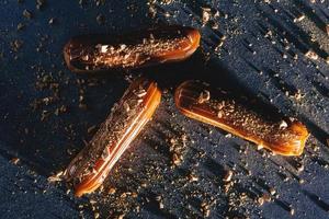 Karamell-Eclairs mit goldenen Streuseln auf dunklem Backgrund. foto