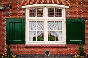 Altes Retro-Fenster mit Fensterläden auf rotem Backsteinhaus foto