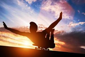 3D junger Mann, der bei Sonnenuntergang auf Skateboard liegt. foto