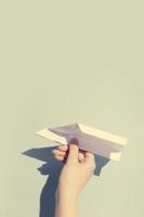 die hand der frau spielt mit dem weißen papierflugzeug foto