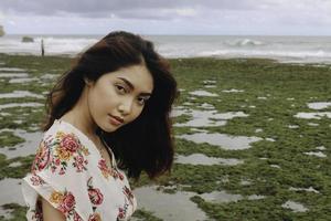 Ein junges asiatisches Mädchen am Strand lächelt in Gunungkidul, Indonesien, in die Kamera foto