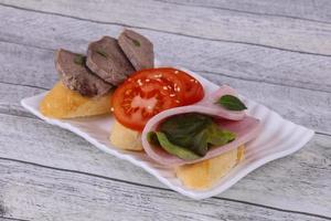 Bruschetta mit Tomate, Schinken und Zunge foto