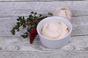 Mayonnaise-Sauce in der weißen Schüssel serviert Thymian und Knoblauch foto
