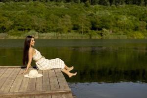 junge frau, die sich auf dem holzsteg am ruhigen see entspannt foto