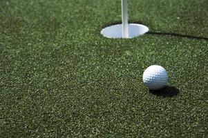 Golfball und Loch auf einem Feld foto