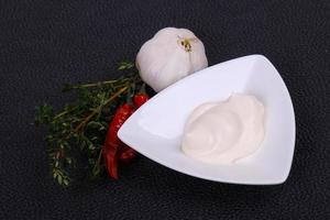 Mayonnaise-Sauce in der weißen Schüssel serviert Thymian und Knoblauch foto