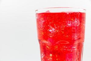 rotes Sprudelwasser mit Eis im Glas auf weißem Hintergrund. foto